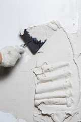 Construction worker puts a gypsum on the wall with a spatula