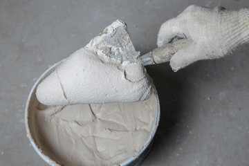 Working tools, spatula in hand on a concrete background, bucket with fresh mortar