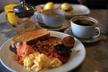 Englisches Frühstück mit Bohnen und Speck auf einer Marmortischplatte im Café