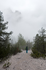 Fototapeta premium young tourist walks on misty mountain path