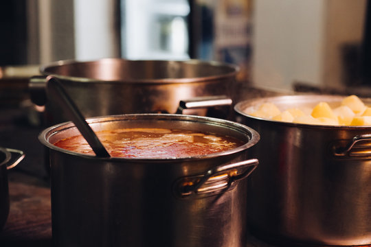 Big metallic pan full of beet soup with big scoop inside standing near pan with boiled potatoes. Looking nourishing, tasty meal, delicious, mouthwatering food. Good for dinner. Home spacy kitchen.