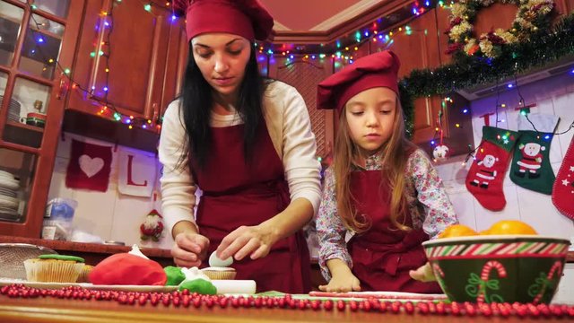 Mother and daughter are making decorations with sugar mastic for cupcake