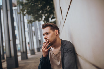 Rauchender junger weißer Mann sitzt auf einer Bank