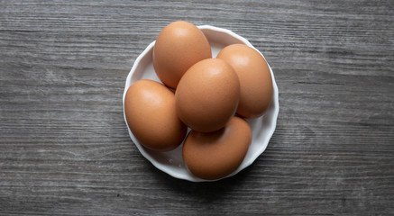 group of eggs in dish on wooden floor.