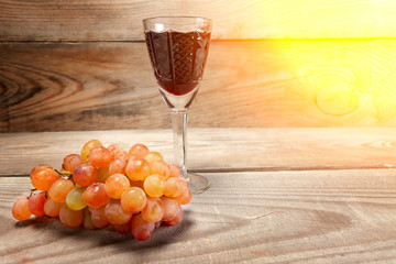 A glass of red wine with grapes on a wooden background.