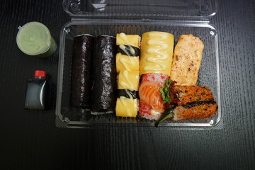 A different assortment of sushi rolls in plastic containers