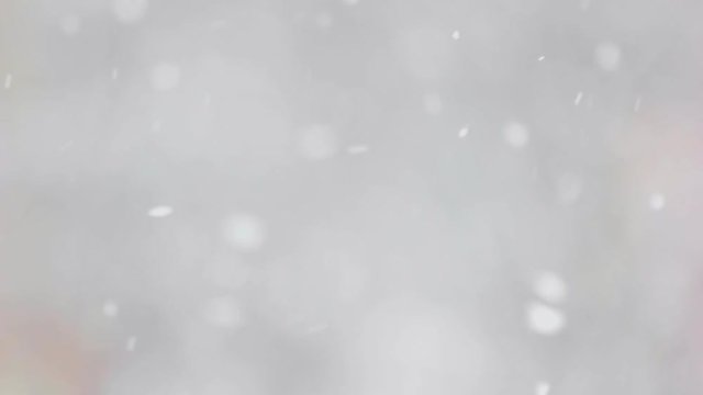 Close up snow particles falling down. Slow motion snow falling on winter blurred background. Snowy winter scene.