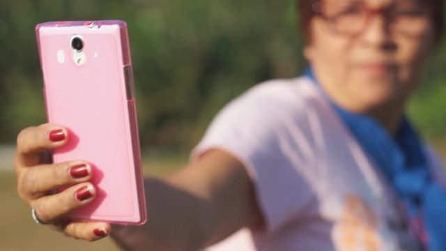 Mature woman self portraits herself with the use of mobile smartphone