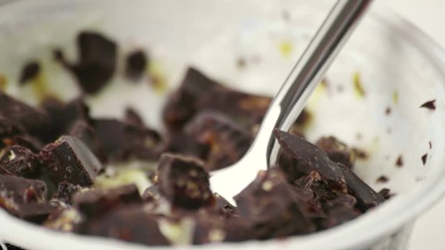 close-up of man use the spoon for eat white yogurt and pieces of brown chocolate, health food diet and nutrition concept