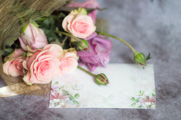 A beautiful bouquet of roses in a package with a postcard for text on a gray background