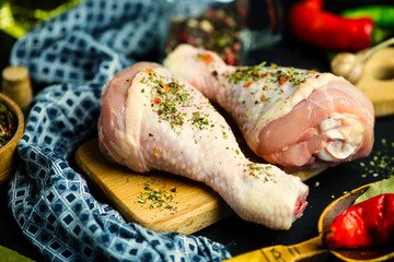 raw chicken legs with spices on a wooden board