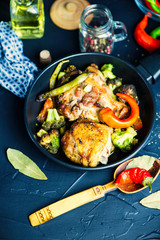 fried chicken thigh with broccoli in a spicy sauce in a pan on a black background