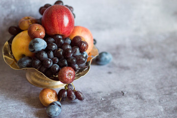  Assortment of fruits in a metal plate on a gray background. Serving natural fresh fruits and...