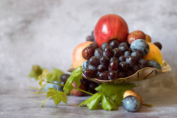  Assortment of fruits in a metal plate on a gray background. Serving natural fresh fruits and...