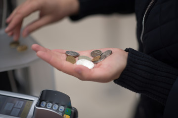 Woman holding golden and silvery coins in her hand at the supermarket. Concept of crisis.