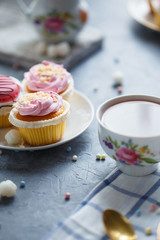 Breakfast on the table. Cakes in the plates, a cup of tea, kettle, milk jug
