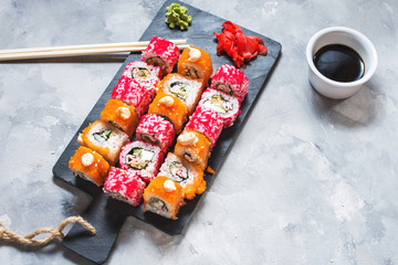 Fototapeta na wymiar Assorted sushi rolls set served on plate on concrete background.