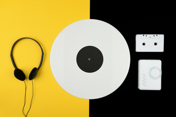 top view of a white long play vinyl record, black headphone and a white audio cassette tape with a...