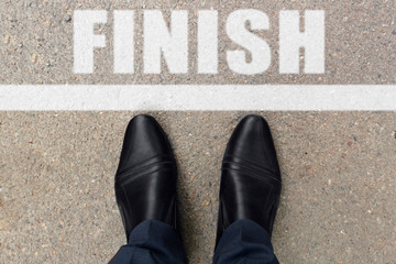 Business concept. Top view of shoes standing on asphalt road with line and word finish. Black shoes...