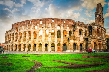 Fototapeta na wymiar ruins of antique Colosseum with green grass lawn in sunise lights, Rome Italy, retro toned