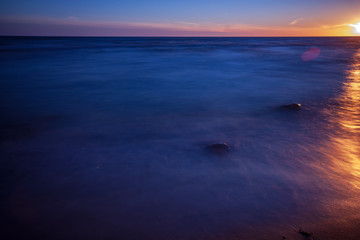 long exposure sea beach with rocks and washed out waves of water