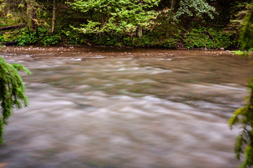 Obraz na płótnie Canvas long exposure rocky mountain river in summer with high water stream level