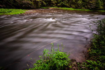 long exposure rocky mountain river in summer with high water stream level