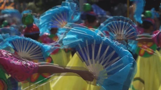 group of carnival folk and cultural dancers in colorful handcrafted coconut costume dance along the streets to honor a patron saint. Public Event