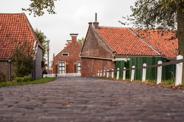 View from approach route over dike on traditional village with farmhouses and old pavements.