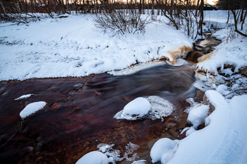 long exposure rocky mountain river in winter with high water stream level