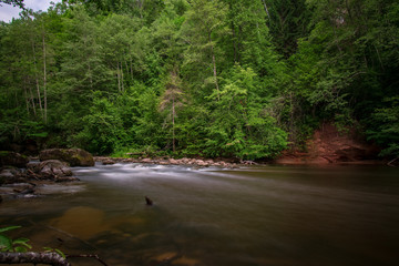 Obraz premium long exposure rocky mountain river in summer with high water stream level