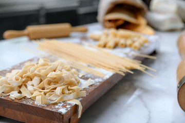 Raw homemade pasta and ingredients for pasta on white marble table top.