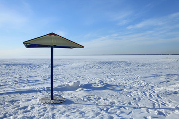 Naklejka na ściany i meble parasol on a winter beach covered in snow and ice