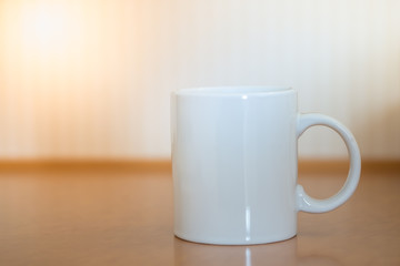 Close up of white mug cup of hot coffee on wooden table.