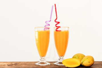 cups with mango juice on wooden countertop