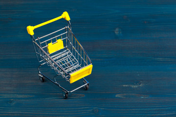 Toy shopping cart on blue wooden background