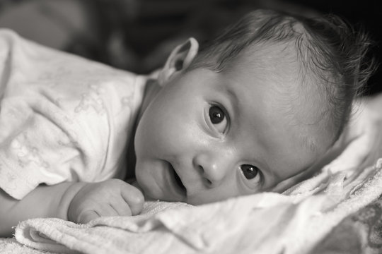 The newborn (one month old baby) lying on the bed. Black white photo