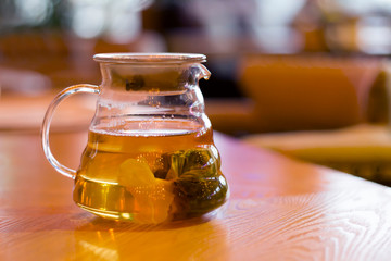 Glass teapot with tea bag on a wooden table in cafe