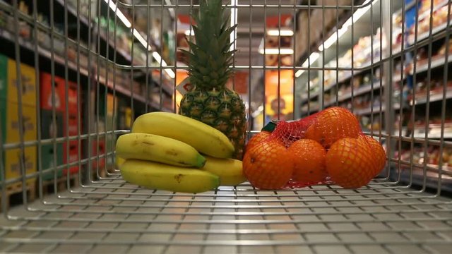 Shopping cart with fruits moving through grocery store
