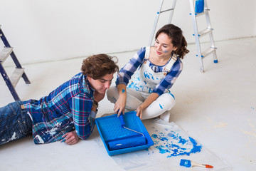 Repair, renovation and people concept - couple going to paint the wall, they are preparing the color and brushes