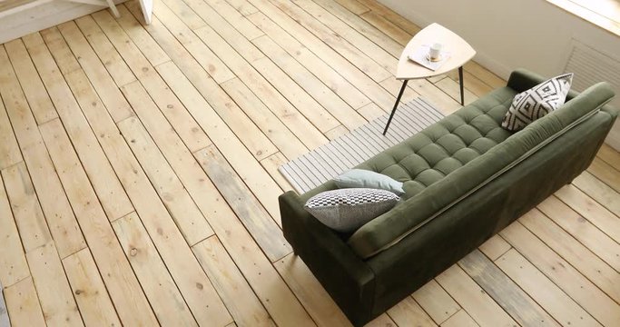 From above shot of comfortable couch and small table standing on wooden floor in spacious living room