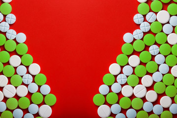 The concept of medicine. Medical green pills. On a red background. View from above .