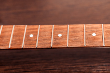 Electric guitar fretboard. On the background of a wooden table.