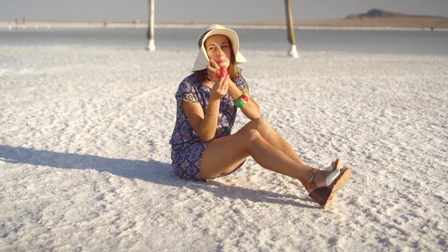 happy smiling girl enjoying the sunset, eating watermelon, sit on salt, pillars