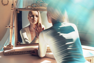 elegant blonde looking at her mirror reflection