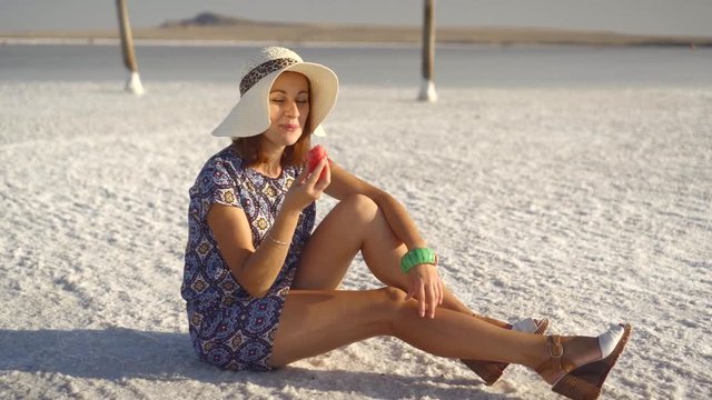 happy smiling girl enjoying the sunset, eating watermelon, sit on salt, pillars