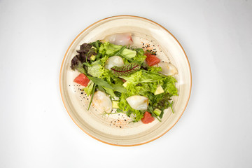 Squid salad and fresh vegetables on a plate on white background