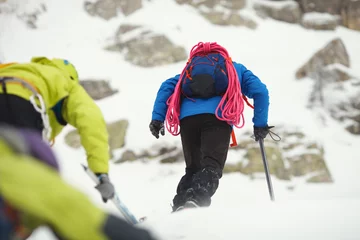 Gardinen Bergsteiger erklimmen bei schlechtem Wetter den schneebedeckten Berghang. © esalienko