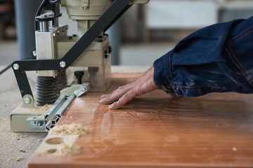 Furniture production concept: man working at machine and making furniture part