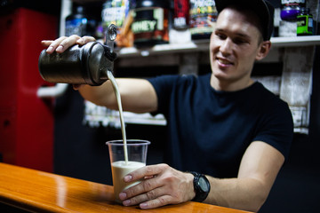 young male athlete making a protein shake. pours it into a glass